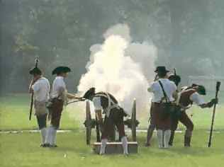Reenactors firing a cannon, enveloped in a cloud of smoke on a grassy field.