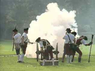 Historical reenactors firing a cannon enveloped in smoke.