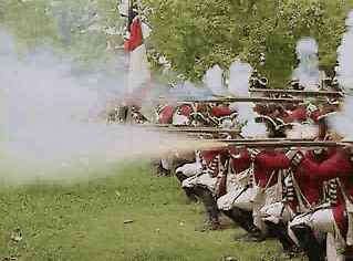 A line of historical reenactors dressed in red uniforms firing a volley, with white smoke trailing from their muskets.